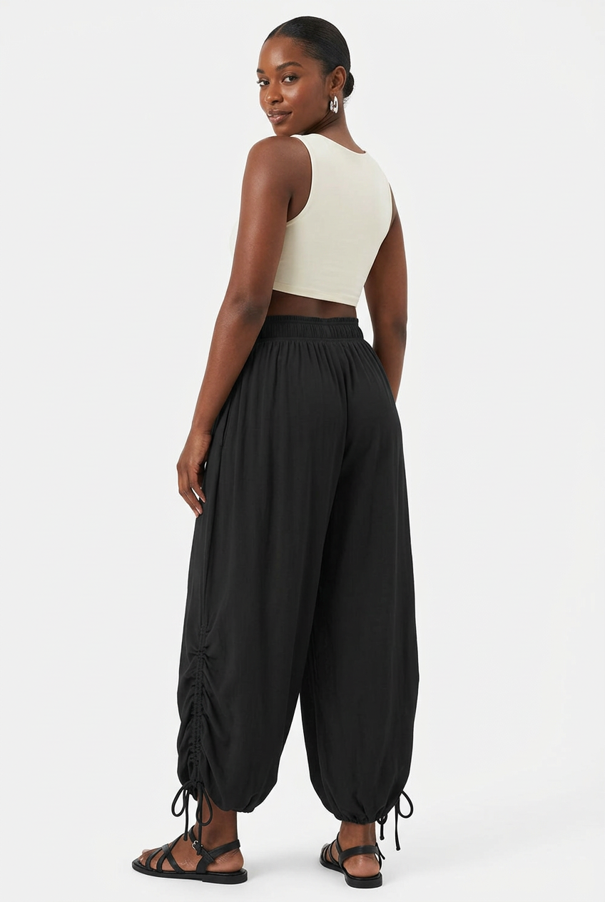 Pantalon noir froncé à cordon porté de dos