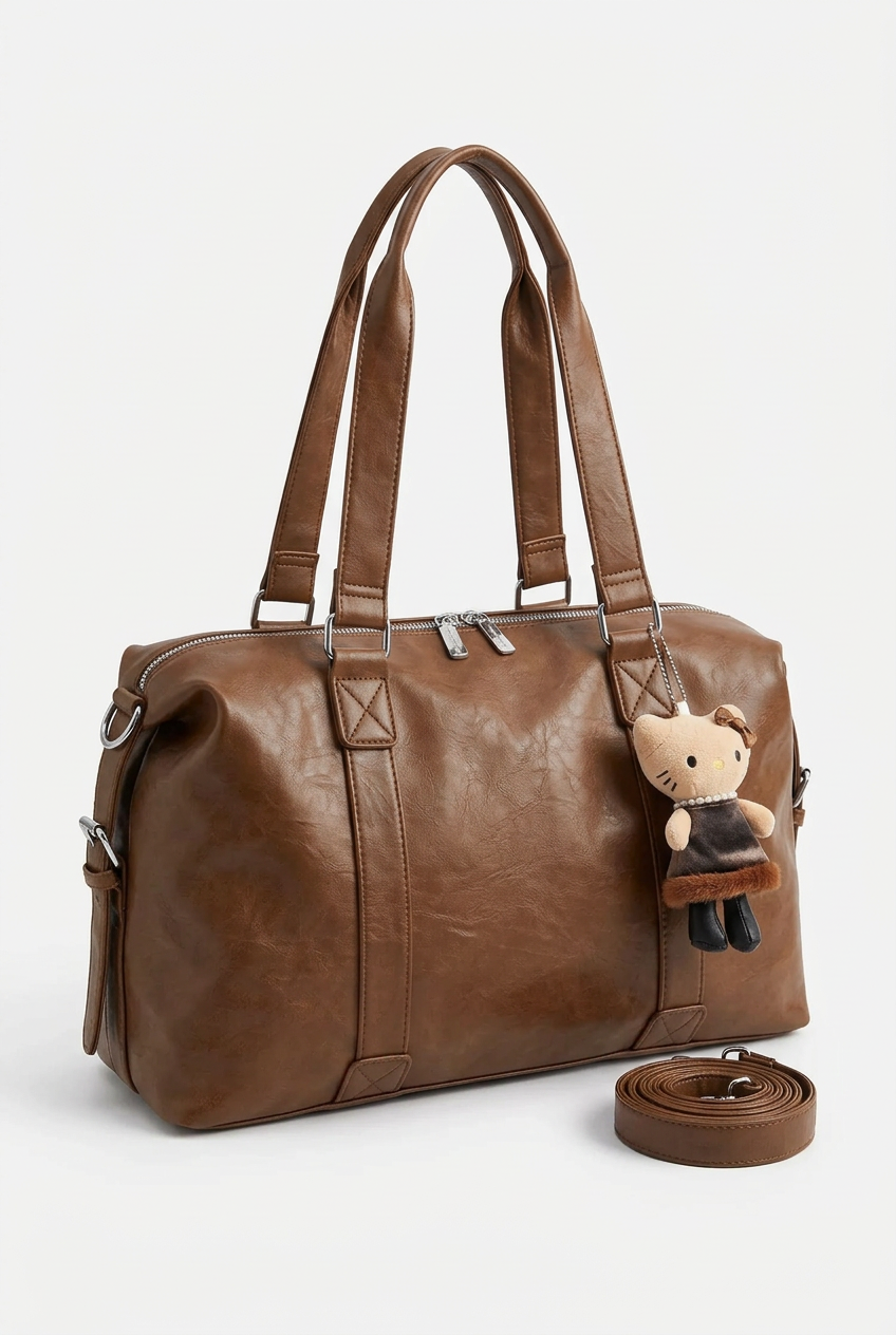 Sac porté épaule caramel avec bijou de sac, seul sur fond studio blanc