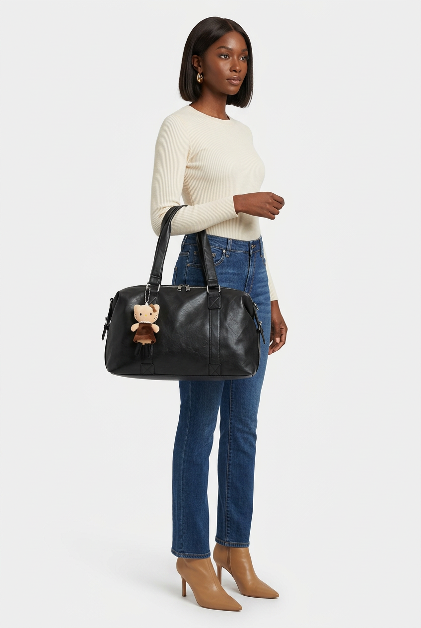Sac noir avec bijou porté à l’épaule, mannequin corps entier sur fond studio blanc