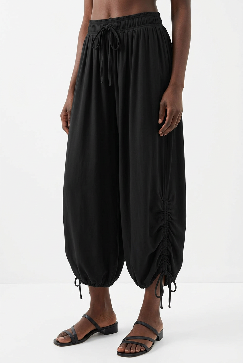 Détail du pantalon noir froncé à cordon, jambes et chaussures