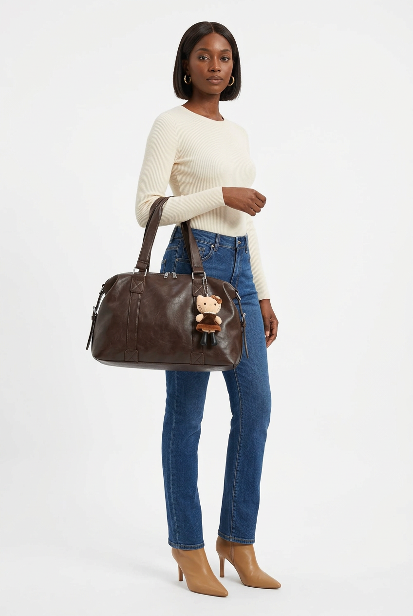 Sac marron avec bijou porté à l’épaule, mannequin corps entier sur fond studio blanc